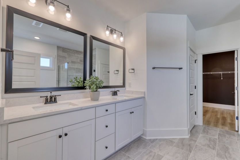 Spa-inspired owner’s bath with dual vanities and modern fixtures.
