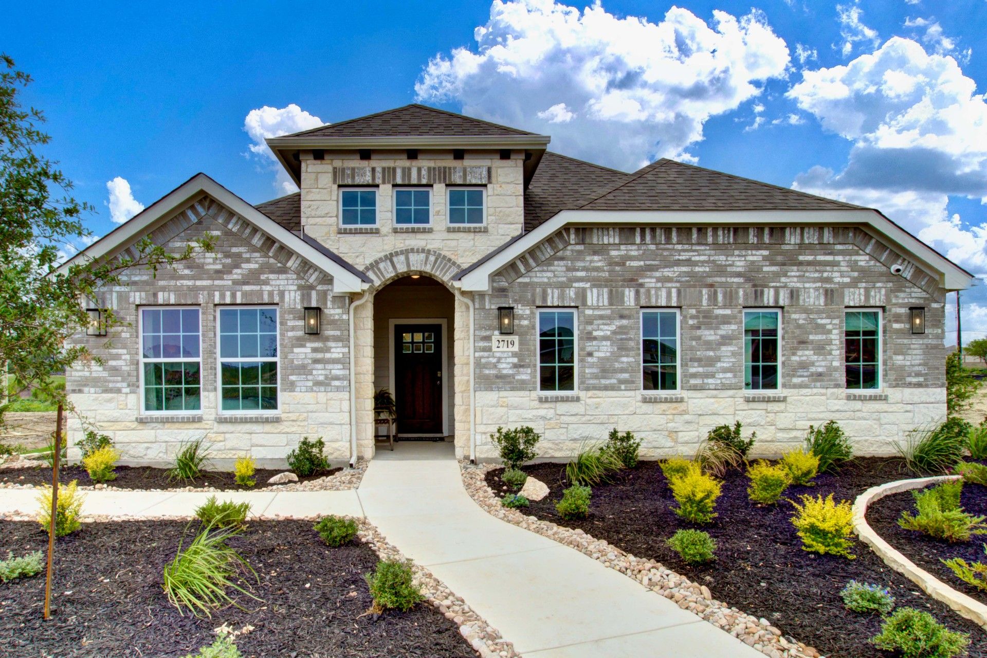 Prairie Green Brick Home with Arched Entrance and Manicured Landscape